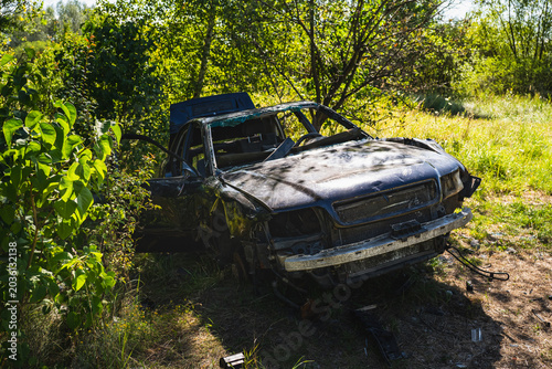 a burnt-out and wrecked car abandoned on the side of the road