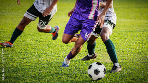 Obraz na plátně Professional soccer players battling for ball possession on an outdoor stadium f