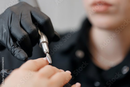 Foto Professional manicure process for young caucasian female - modern nail care tech