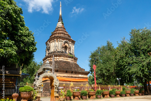 Tableau sur toile A majestic weathered ancient brick chedi stands tall against a clear blue sky, surrounded by green trees
