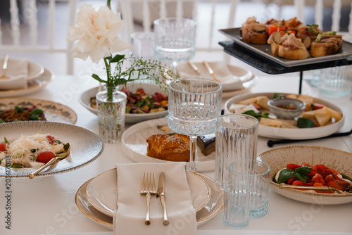 Elegant Fine Dining Table Setting with Appetizers, White Flowers, and Crystal Glassware in Bright Light
