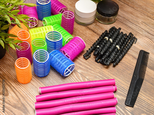 bright plastic rollers and pink hair curlers on a wooden table