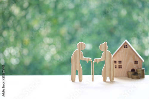 Fotografija Couple wooden figures standing with a miniature house and coins, representing retirement home planning, property investment, real estate for seniors and financial security for old age