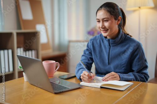 Fotografija Young Asian woman learning remotely, happily studying with laptop and notebook a