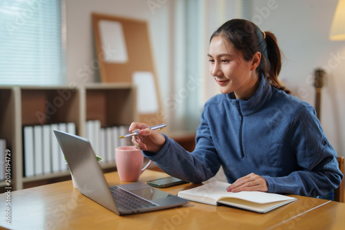 Obraz na płótnie Young Asian woman working from home using laptop, studying online, participating