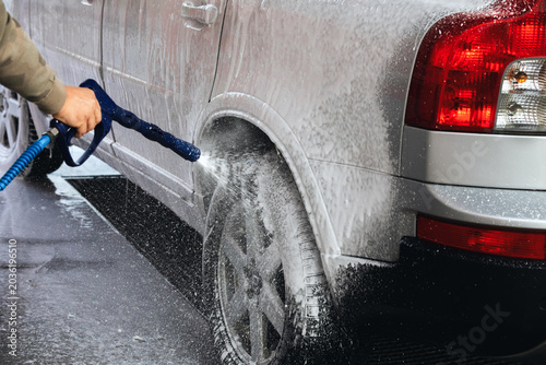 Car washing with a high pressure water jet at an outdoor self-service  car wash station.