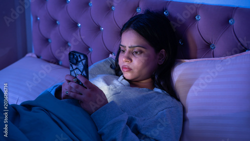 Indian Woman Using Phone Late at Night Lying in Bed in Dark Bedroom