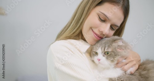 A loving pet owner gently cuddles her fluffy cat at home, finding comfort and showcasing the special bond and therapeutic companionship with her furry friend.