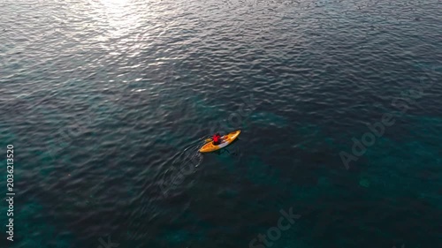 Aerial view of a woman relaxing on a yellow kayak over a beautiful coral reef in crystal clear turquoise sea water background