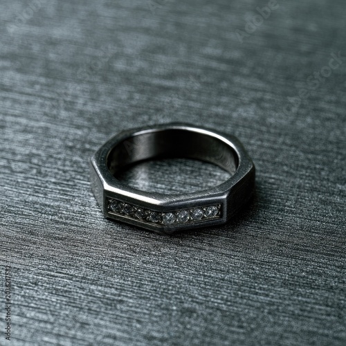 A faceted band ring with inlaid stones on a textured surface