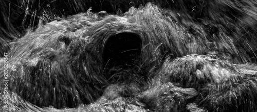 Black and white image of backlit water spraying in slow motion from a waterfall.