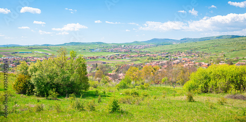 Photography Bright spring landscape of rolling green fields and trees overlooking a small vi