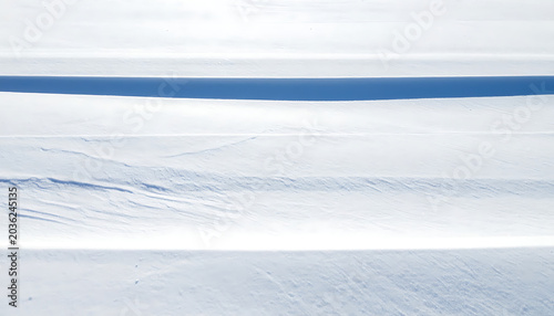 Abstract winter scene with layered snow drifts and shadows, crisp texture, natural light, minimalist cold atmosphere