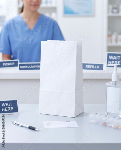 Blank pharmacy paper bag mockup at healthcare pickup counter with appointment card
