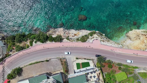 Top-down aerial video showing a winding seaside road and the blue waters of Ionian sea in southern Vlora, Albania.