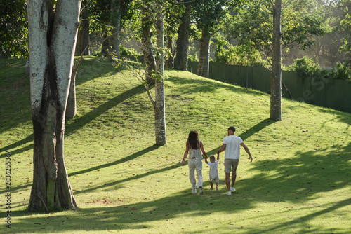 Family enjoying peaceful walk across sunny green park.