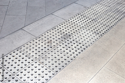 Foto Tactile paving path with warning bumps for visually impaired people on a city sidewalk
