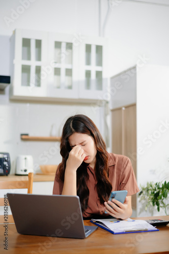 Asian business woman is stressed, bored, and overthinking from working on a tablet at the office.