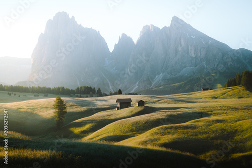 Scenic alpine mountains scenery with meadows and traditional mountain huts in the Alps in golden morning light at sunrise in summer