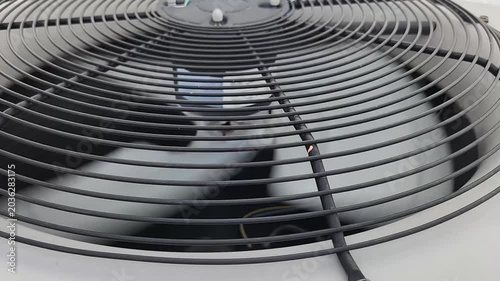 Detailed video clip of a rotating fan inside an outdoor air conditioning condenser unit. Cooling and ventilation equipment operating during residential climate control.