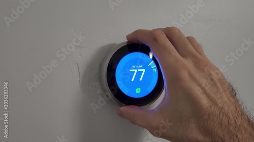 Person operating smart thermostat for home climate control