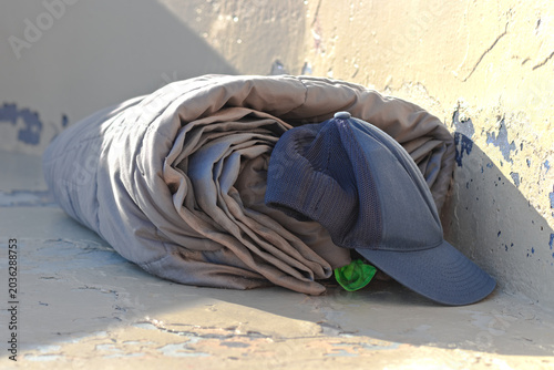 Vászonkép Rolled bedding and a cap sit in a worn urban corner, suggesting homelessness in Long Beach