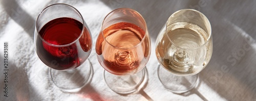 Top down view of three wine glasses filled with red rosé and white wine for elegant beverage background and banner design