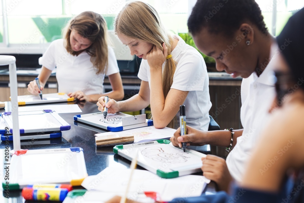 Fototapeta premium Students focused on drawing in a classroom setting.
