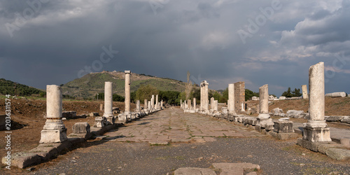 Sacred Way ruins at Asklepion, Pergamon, Bergama, Turkey. Ancient columns line a stone path leading to distant ruins under a blue sky