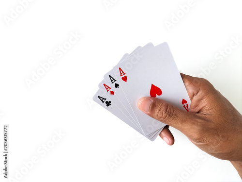 Close-up of a hand holding full set of four aces over a white table.