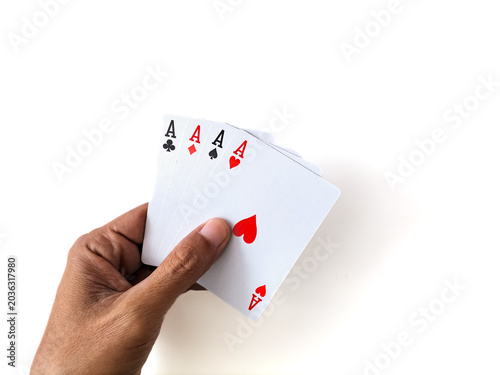 Close-up of a hand holding full set of four aces over a white table.