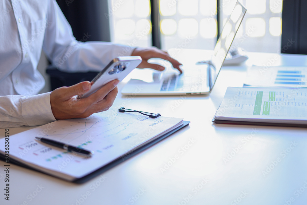 Fototapeta premium Professional businessman, entrepreneur or accountant working on a financial report paperwork at his desk, using mobile phone.