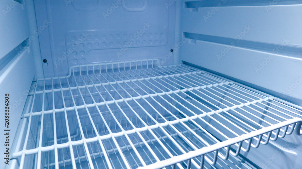Fototapeta premium Interior view of an empty clean refrigerator looking slightly to the right side of wire shelves