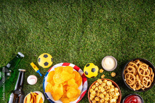 International football soccer championship background, soccer matches cheering concept with beer bottles, party snacks chips, popcorn, pretzel, nuts, whistle and soccer ball, american flag, copy space