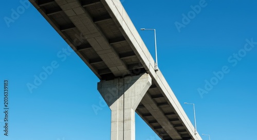 A highway bridge stretches across a clear blue sky with no traffic visible.