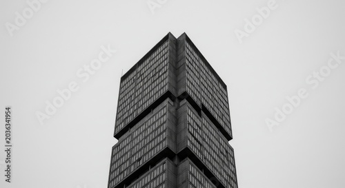 A tall building stands alone in the city under a gray sky.