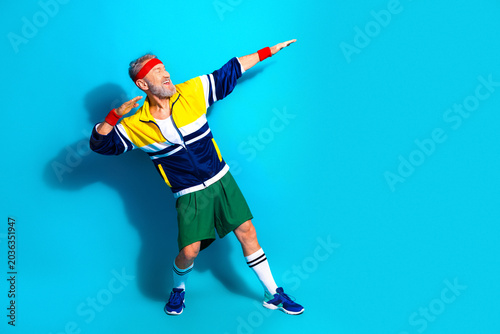 Tableau sur toile Active senior man striking a triumphant retro athletic pose in colorful tracksui