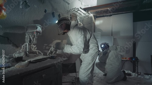 Scientist in hazmat suit inspects lab sample on frostcovered bench, dim headlamp illuminating cracked vials, rusted equipment, dustswept instruments inside abandoned house laboratory careful gloved