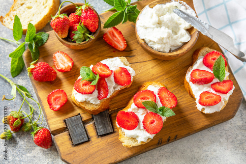 Bruschetta with ricotta and strawberry on a stone tabletop. Berries toast summer breakfast, healthy food.