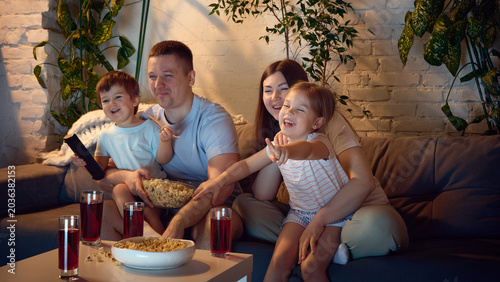 Fotografía Family movie night with children pointing at screen in living room