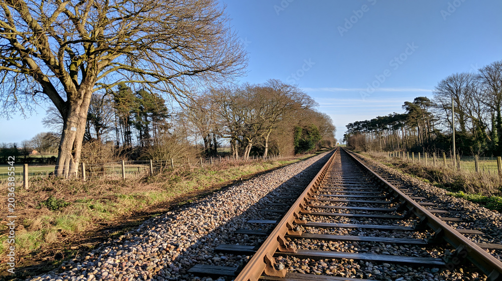 Fototapeta premium trackbed. A long stretch of railway trackbed with gravel and sleepers receding into distance. mobility guides, transit brochures, designed for mobility and urban transit guides.