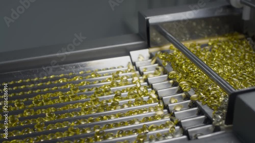 Drug Production. Medical production of dietary supplements. The yellow gel gelatin capsules move on an automatic conveyor. Creation of tablets and medicines at the factory.