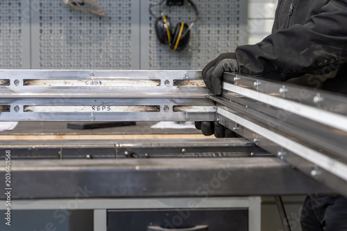 Assemblage et ajustement de profilés métalliques en atelier de fabrication, réalisé par un professionnel de la métallerie pour la création de structures sur mesure.