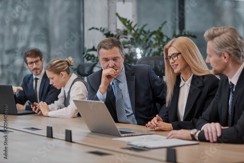 Five professionals gather around a long wooden table