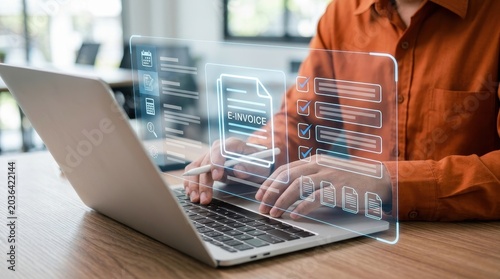 Person using a laptop to manage e-invoices with a futuristic holographic interface, digital transformation concept.