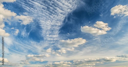 Cinematic cloudscape timelapse with wispy and cumulus clouds flying across the bright blue sky.