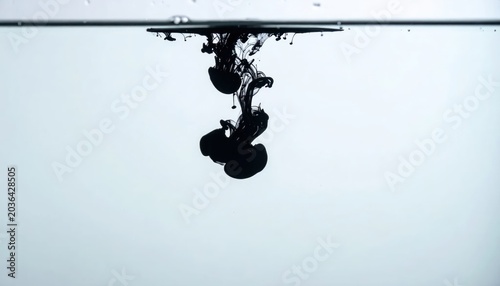 Black Ink Droplets Spreading Underwater in Minimal White Studio Background