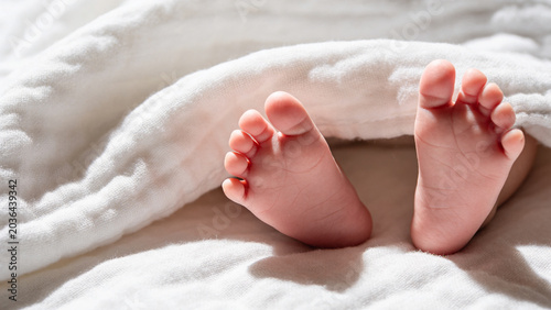 Baby feet resting on soft white blanket in serene environment  