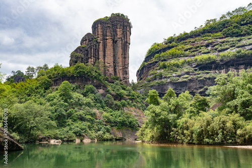 A serene river flows past the towering rock formations in the scenic Wuyi Mountains located in Fujian China