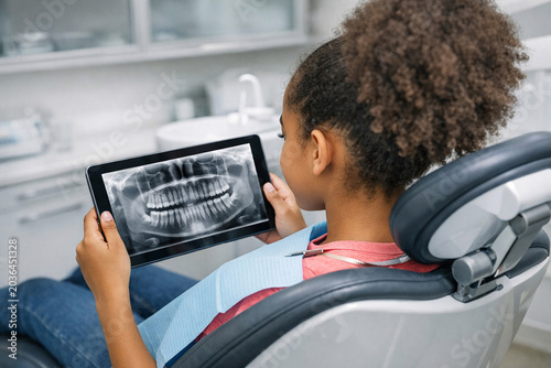 Young girl looking at her teeth x-ray during dental visit.